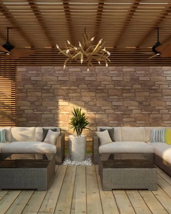 This outdoor seating area shows how texture and materials can define a space. The combination of a rough stone wall, smooth wooden decking, and comfortable wicker furniture creates a rich, tactile experience.