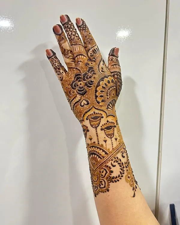 This elegant back-hand design extends up the arm, featuring beautiful jhumka (earring) motifs. The combination of floral patterns and delicate chains creates a jewelry-like effect.