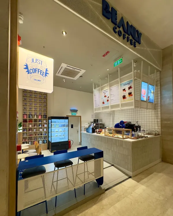 A wide shot of the Beanly cafe, showing how we translated the online brand into a physical space. The design balances the bold electric blue counter with warm wood tones and a clean, white service area, creating a welcoming and energetic atmosphere.