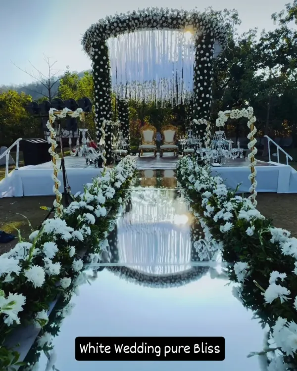 This all-white wedding mandap with a stunning mirrored aisle creates a feeling of pure bliss. It's a perfect example of how we can transform an outdoor lawn into a breathtaking, elegant ceremony space.
