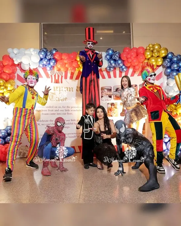 I can arrange a full lineup of entertainers to make your party unforgettable. Here, clowns on stilts, jugglers, and even Spider-Man characters pose with the family at a lively carnival-themed birthday.