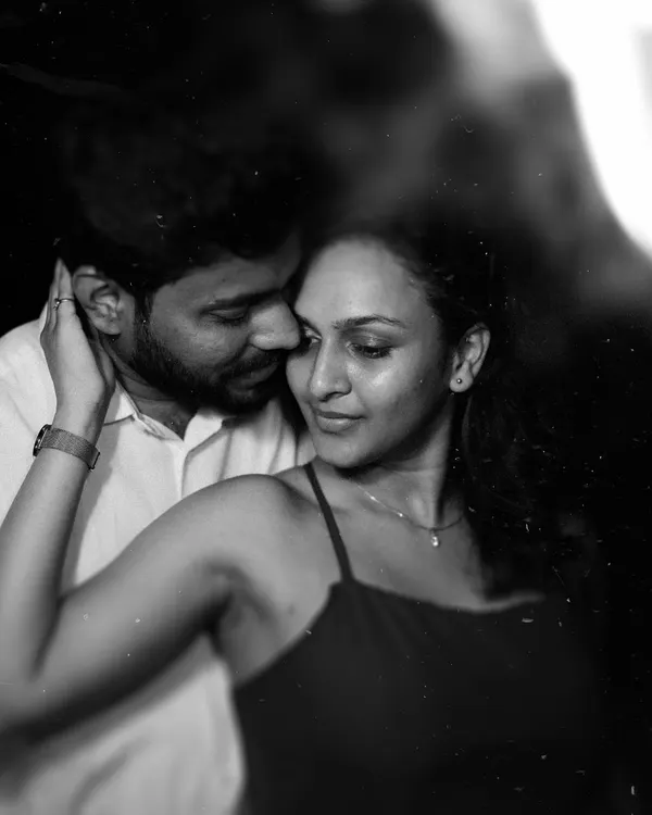 A timeless black and white close-up of a couple in a tender embrace, lit softly in the dark. This artistic portrait focuses on pure emotion and connection, showcasing a classic and intimate style of couple photography.