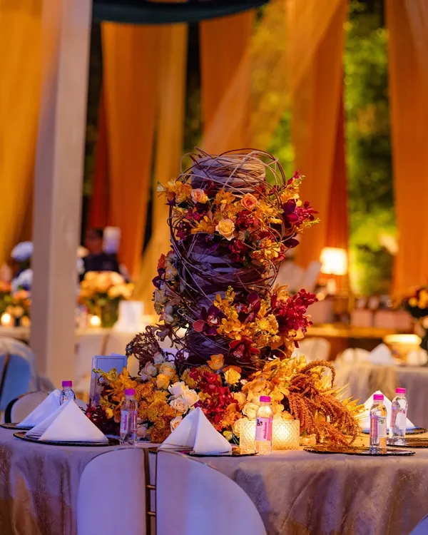 This sculptural centerpiece was inspired by the work of international designer Hitomi Gilliam. It utilizes midollino extenders to create a woven, nest-like structure from which autumn-toned flowers appear to grow organically.