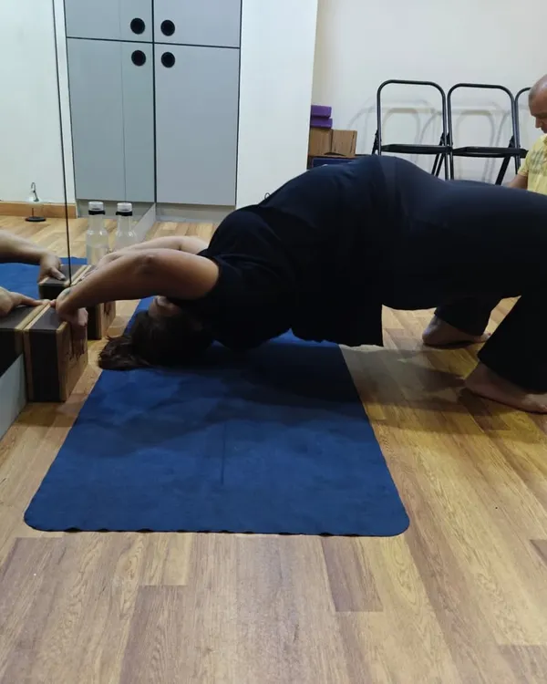 Here, a student uses yoga blocks for support while moving into Chakrasana (Wheel Pose). The blocks provide stability for the hands, allowing for a safer and deeper backbend by ensuring the shoulders are properly supported.