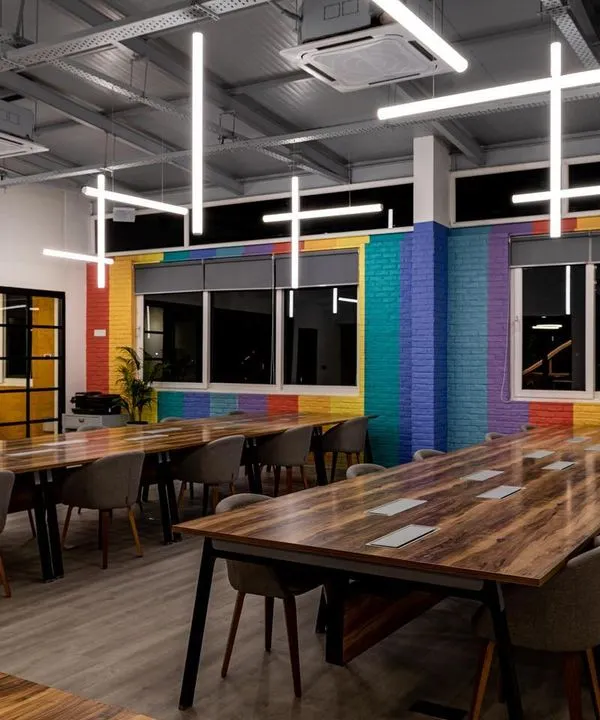 This open-plan workspace features a custom installation of suspended LED tubes. The arrangement is designed to provide excellent, uniform light for working while creating a sense of energy and movement that reflects a modern, dynamic company culture.