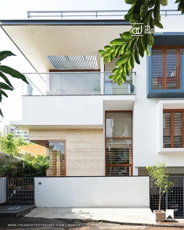 The front elevation of the Cube House. The design uses clean white planes, travertine cladding, and carefully placed windows to create a modern and inviting facade on a compact city plot.