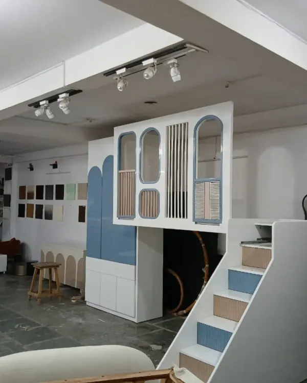 A wider view of the custom loft bed in our workshop, showing the stairs and the integrated wardrobe. This all-in-one solution is designed to maximize floor space while creating a fun and imaginative environment.