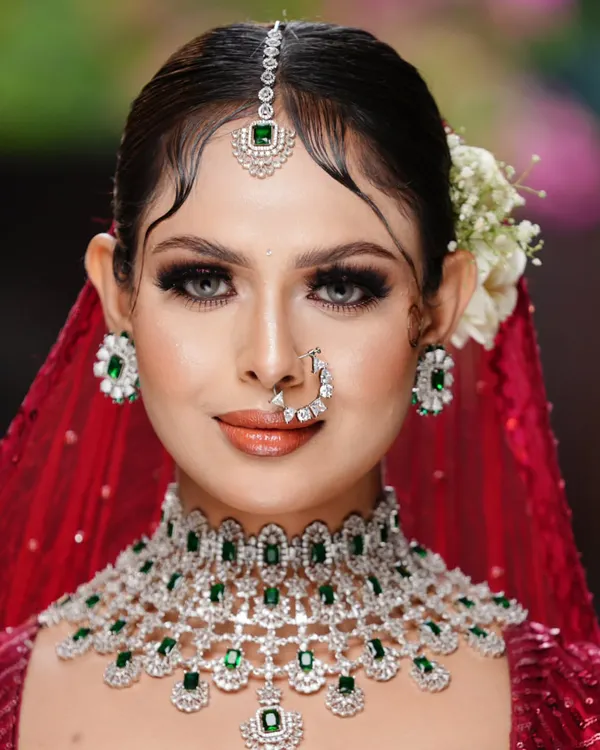 A picture of bridal perfection. This student's work showcases a classic look with emerald jewelry, featuring sharp winged liner, soft contouring, and a glossy nude lip, ideal for the modern bride.