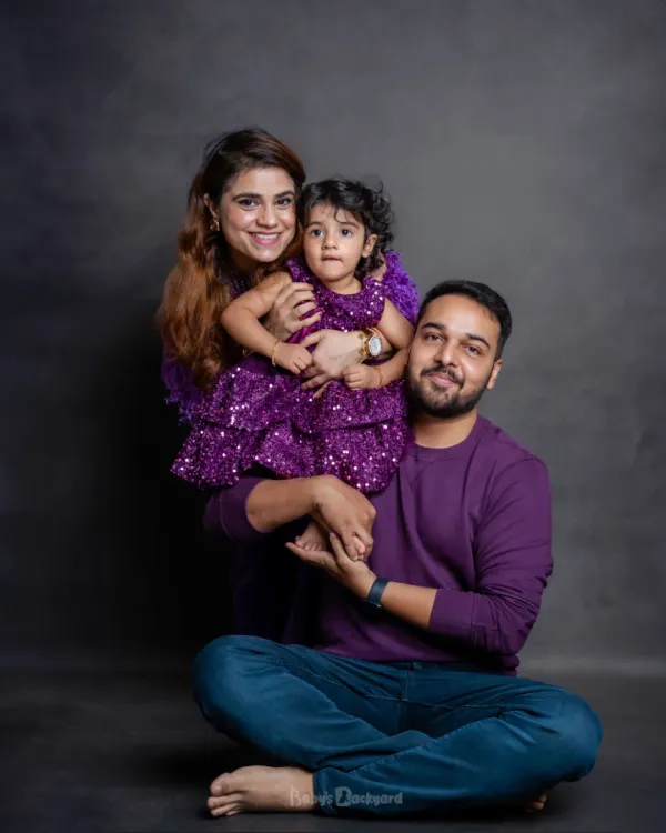 A family that glows together, grows together. The coordinated purple outfits look wonderful against our simple studio backdrop, making their smiles shine.