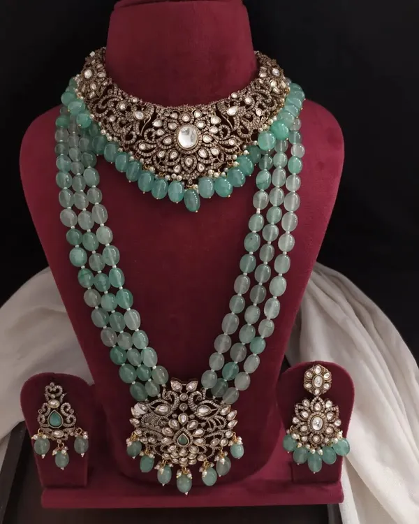 This stunning Victorian-inspired jewelry set features a choker and a matching long beaded necklace in a beautiful pastel green. The intricate metalwork is studded with stones for a grand, royal look.