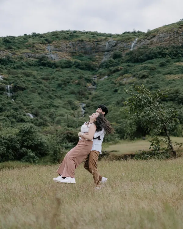 A joyful, carefree twirl in the middle of a lush green meadow, with mountains in the background. This photo is full of movement and happiness, perfectly capturing a spontaneous moment of love.