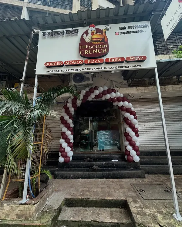 A classic spiral balloon arch in maroon and white perfectly frames the entrance for the grand opening of 'The Golden Crunch' restaurant, creating an inviting and festive look.