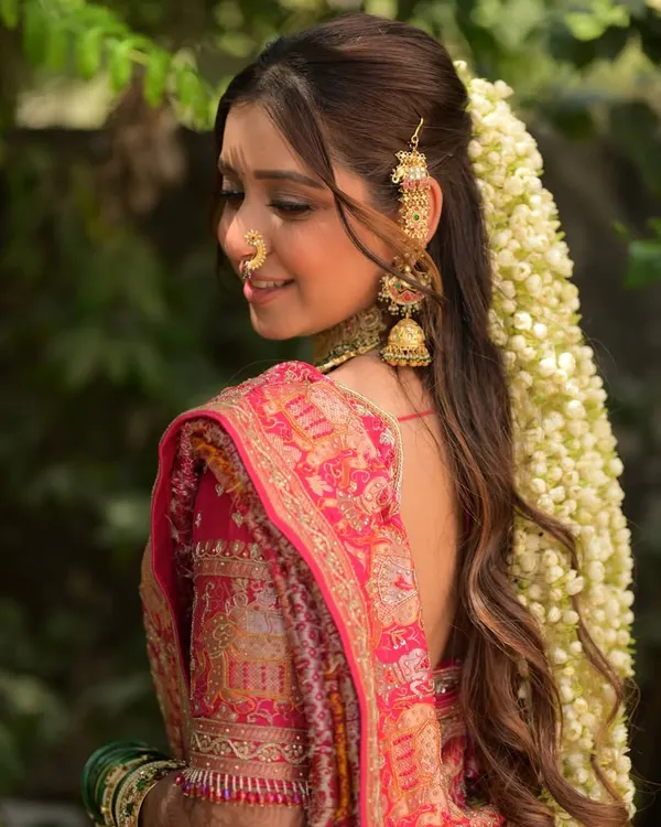A close-up of this stunning bridal hairstyle. The cascade of fresh jasmine flowers, known as gajra, paired with a traditional hair accessory, creates a look that is both romantic and timeless.