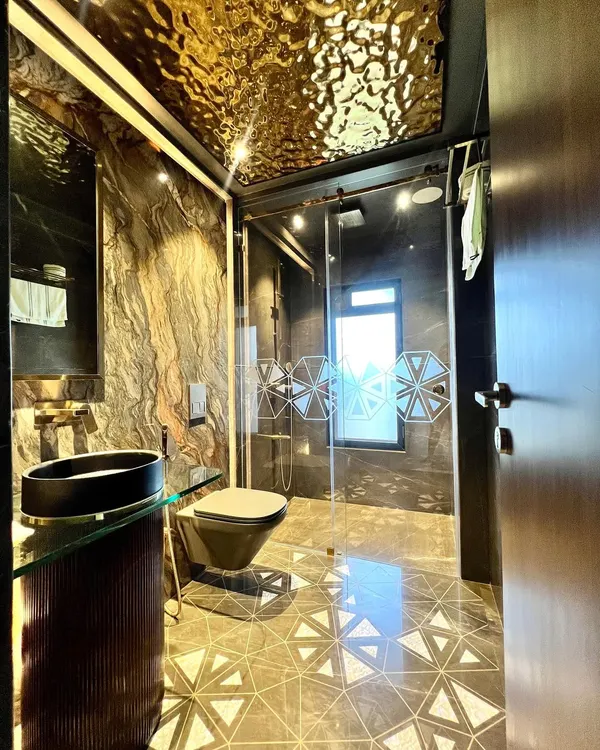 This bathroom is a statement in glamour. We used a liquid metal-effect ceiling, dark marble walls, and mother-of-pearl floor inlays to create a space that is truly magnificent and opulent.