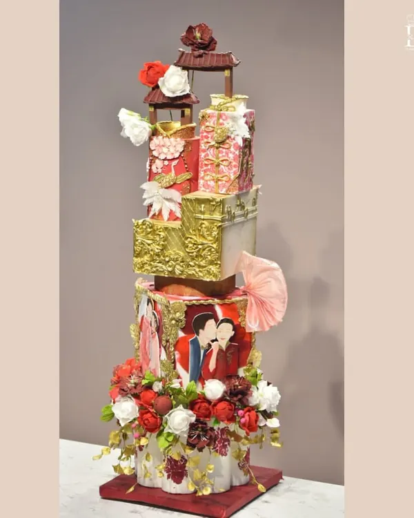 This is the 'Empress of Blossom,' a regal and towering wedding cake that was a true labor of love. It features multiple tiers with intricate gold detailing, hand-painted elements, edible fabrics, and a cascade of fresh flowers, all coming together to create a one-of-a-kind centerpiece for a grand celebration.