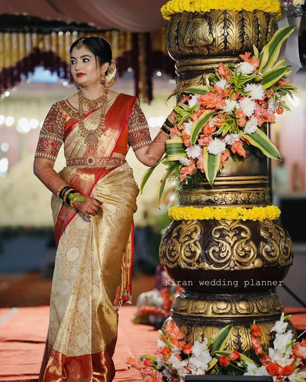 A bride posing next to a large, ornate pillar, a decorative element that adds grandeur to the entrance or stage area.