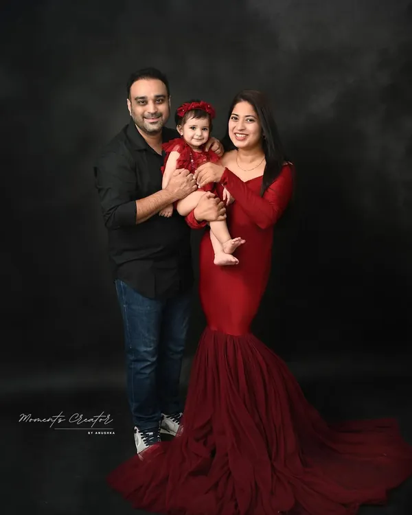 A classic family portrait against a dark, moody backdrop. The coordinated red and black outfits create a striking and elegant look, perfect for a timeless piece of wall art.