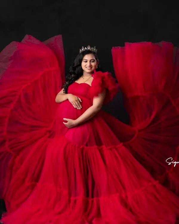 A classic studio portrait in a dramatic red gown. The fanned-out fabric and regal crown create a truly show-stopping image.