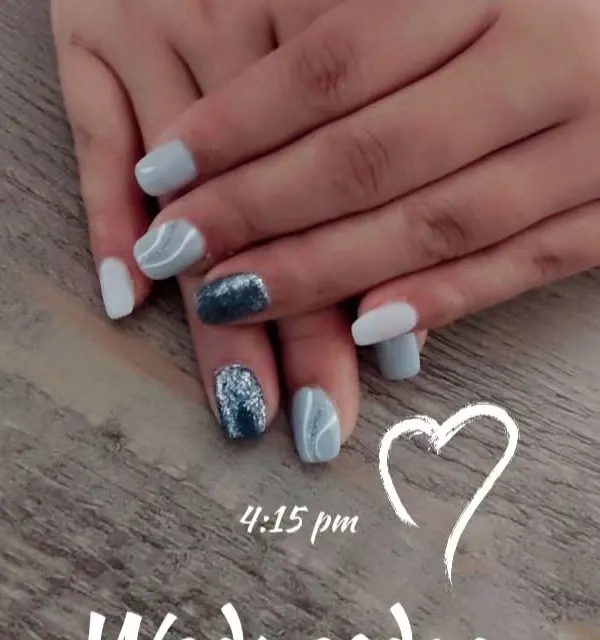 A chic set in shades of grey and white, featuring a bold, dark blue glitter accent nail and subtle white swirl art.