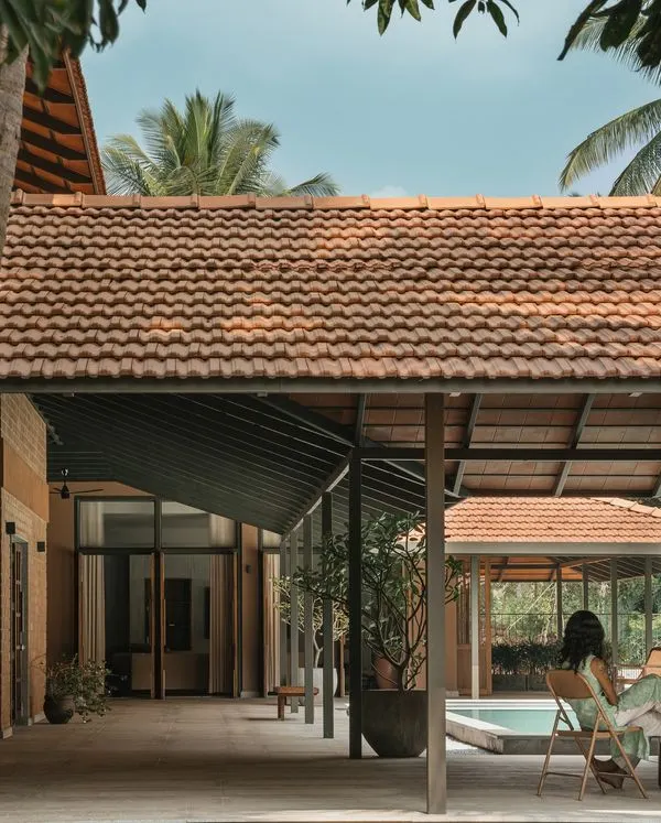 An expansive view of Villa Maati, a peaceful sanctuary we designed within a coconut farm. The open-air corridors and seating areas are positioned to offer relaxing views of the central pool and surrounding landscape.