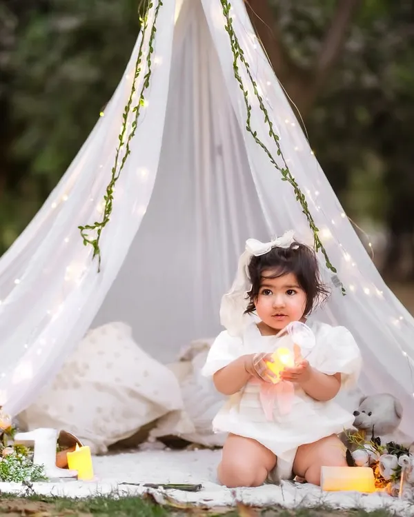 A magical pre-birthday session under a canopy of fairy lights. This outdoor tent setup creates a dreamy and whimsical atmosphere for celebrating your little one.