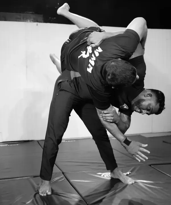 A powerful takedown in action. This black and white shot captures the moment a fighter executes a throw, demonstrating a key skill in wrestling and judo for MMA.