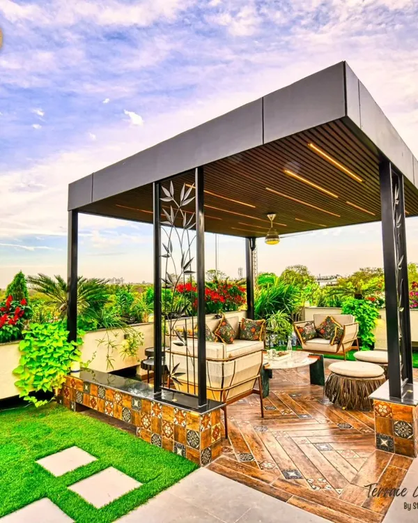The heart of this terrace garden is the cozy seating area under a modern pergola. We added handcrafted metal art panels with a bamboo motif and a small water feature to create a warm, inviting oasis for our clients to unwind every day.