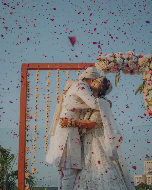 A shower of petals for a lifetime of happiness. This Varmala moment, captured against the sky, is one of our favorite shots to take, symbolizing the community's blessing on the couple.