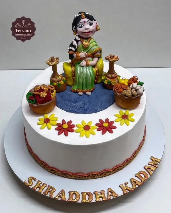 A traditional Godh Bharai (baby shower) cake. This design features a hand-sculpted fondant figure of an expecting mother in traditional attire, surrounded by auspicious items.