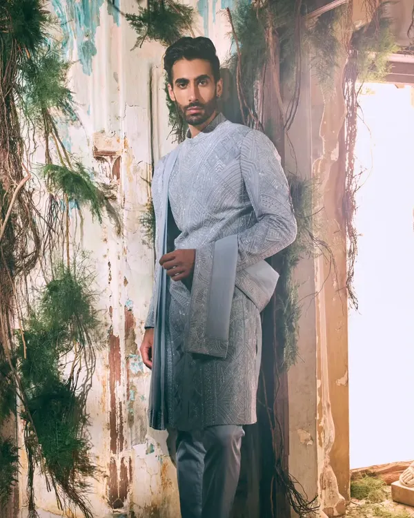 This textured ensemble in a serene, cool tone exemplifies quiet sophistication. The tailored silhouette and intricate fabric offer a modern take on traditional menswear, perfect for a groom or wedding guest who prefers understated elegance.