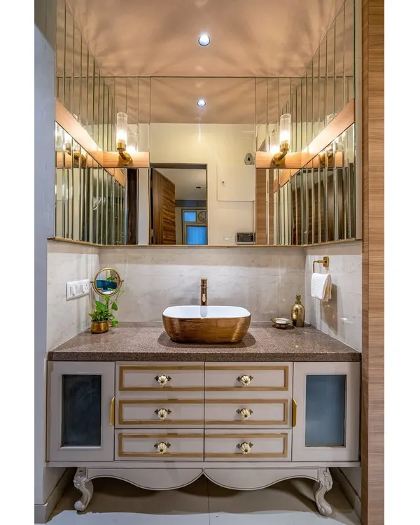 An opulent and functional vanity area. We designed this custom piece with classic carved legs, ornate drawer knobs, and a beautifully lit mirror to create a luxurious space for daily rituals.