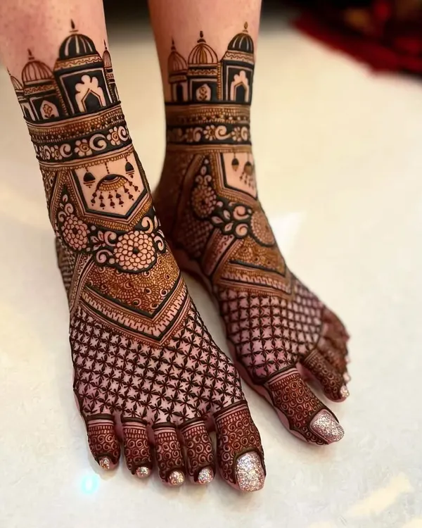 This foot mehandi features bold architectural dome (gumbad) patterns on the ankles. The design combines a dense checkerboard (jaali) pattern on the foot with clean, open toes.