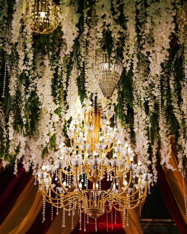 A magnificent crystal and floral chandelier, serving as a grand centerpiece and bathing the event in warm, elegant light.