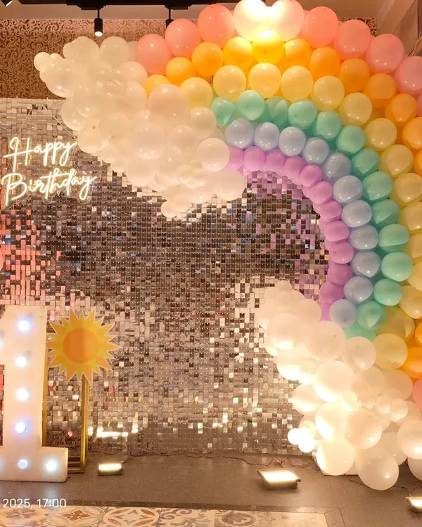 This vibrant rainbow theme for a first birthday is one of our most popular setups. We created a full pastel balloon rainbow arch against a silver shimmer wall, complete with a custom "Happy Birthday" neon sign and a large light-up marquee number '1' for the perfect photo opportunity.