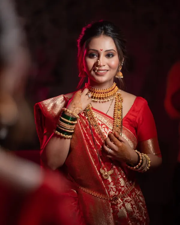 A stunning bridal portrait, with the bride looking in a mirror, her face illuminated by soft light, highlighting her beautiful makeup and jewelry.