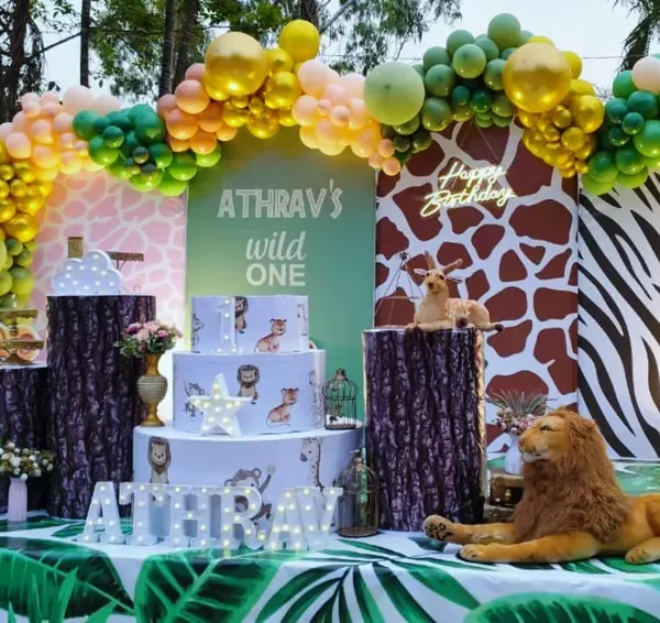 We created a wild one's paradise for Atharv's first birthday with this spectacular jungle safari theme. The setup features a lush organic balloon arch in jungle tones, custom animal print backdrops, and life-sized animal props like the friendly lion and zebra to create an immersive safari adventure.