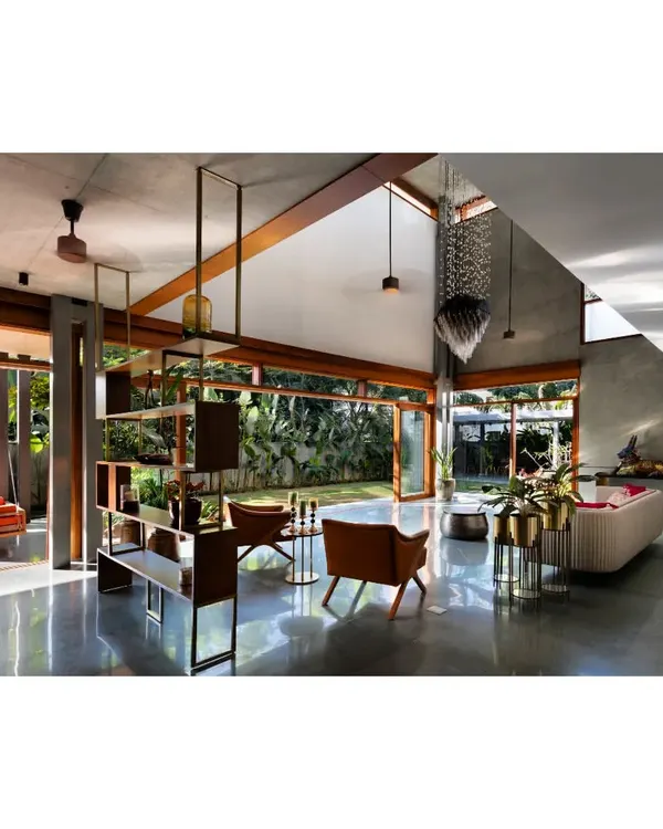 This living space from the 'House of Canopies' in Bangalore is the heart of the home, designed to dissolve the boundaries between inside and out. The double-height ceiling and expansive glass walls frame the lush garden, while the polished concrete floor reflects the changing light, creating a serene, open atmosphere. It's a clear expression of my passion for tropical modernism and creating homes that breathe.