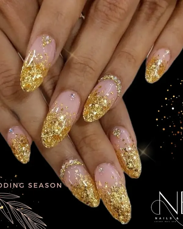This is the ultimate glamorous look for the wedding season. It features a heavy cascade of chunky gold glitter over a sheer nude base on long, almond-shaped nails.