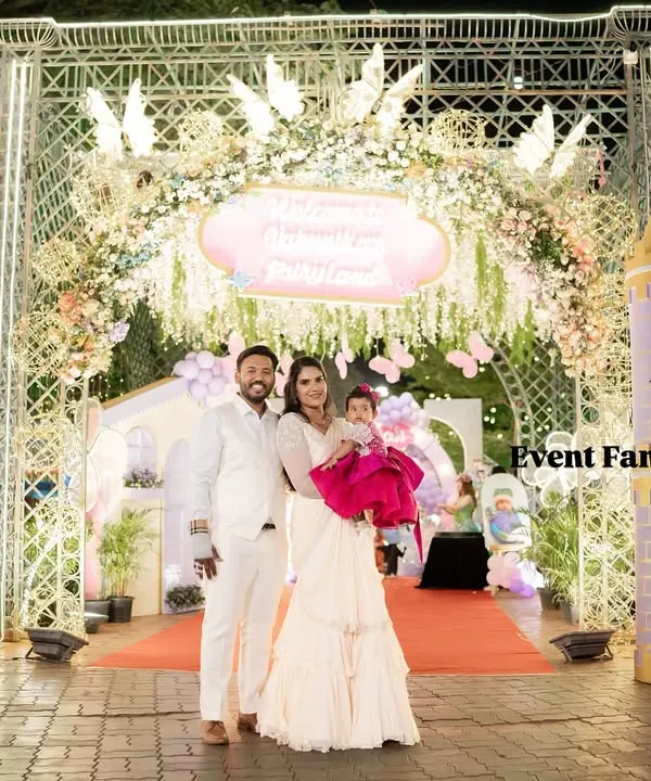 A breathtaking entrance to Varnnika's fairyland, featuring two large castle turrets and an ornate archway decorated with flowers. The family stands together, ready to welcome guests to the royal celebration.