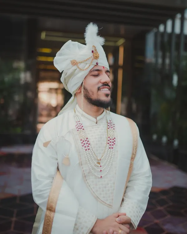 A classic portrait of a Maharashtrian groom on his wedding day. With his eyes closed and a peaceful smile, this shot captures a moment of quiet anticipation before the ceremony begins.