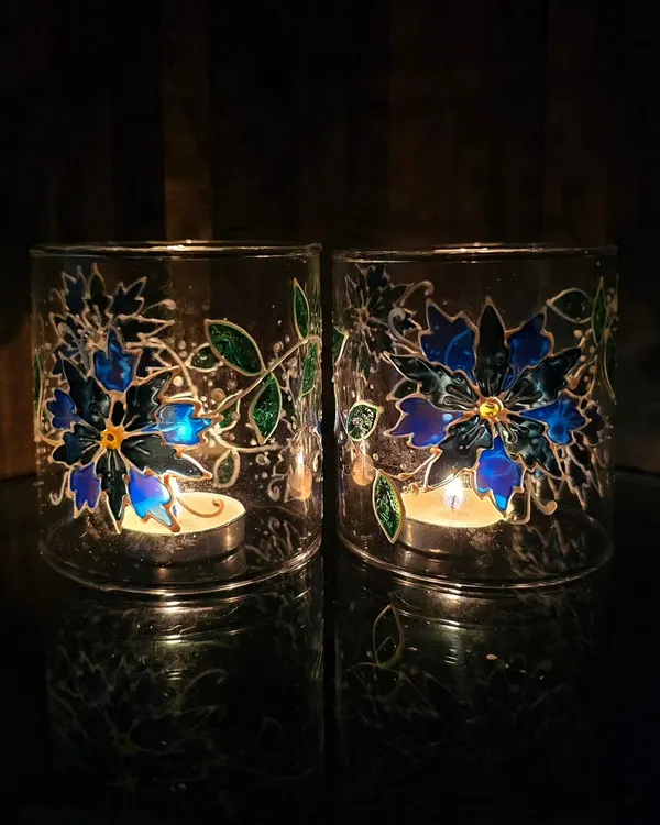 The magic happens when you light a candle inside. These lamp chimneys, painted with blue flowers, create a beautiful, glowing effect that's perfect for festive evenings.