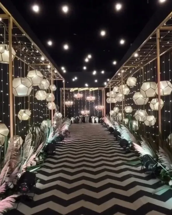 I designed this grand entrance for a corporate annual event, creating a memorable walk-in experience. The setup features a custom golden framework, geometric lanterns, and dramatic fairy lights over a bold chevron-patterned carpet to set a sophisticated and modern tone.