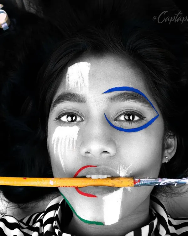 A striking black and white editorial portrait with selective color on the face paint. This high-concept image plays with contrast and focus, creating a memorable and artistic shot for a fashion story or a model's creative portfolio.