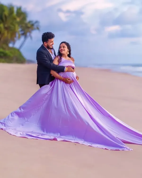 A beautiful portrait of togetherness on the beach. The mom-to-be wears our flowing lavender infinity gown, while her partner looks sharp in a classic black suit, creating a perfectly balanced and elegant couple's maternity photo.