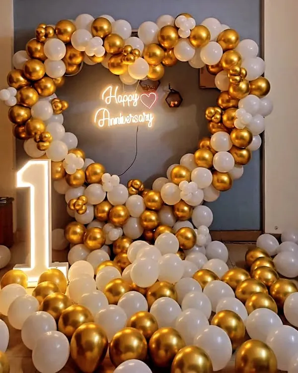 This classic gold and white heart-shaped balloon arch is perfect for a first anniversary party. The large light-up marquee number makes for a great photo opportunity and adds a personalized touch to the celebration.