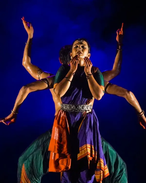 A powerful visual from 'Nagamandala' where multiple bodies create a single, divine form. This kind of group choreography requires perfect synchronization and a deep understanding of spatial dynamics to achieve a striking visual effect.