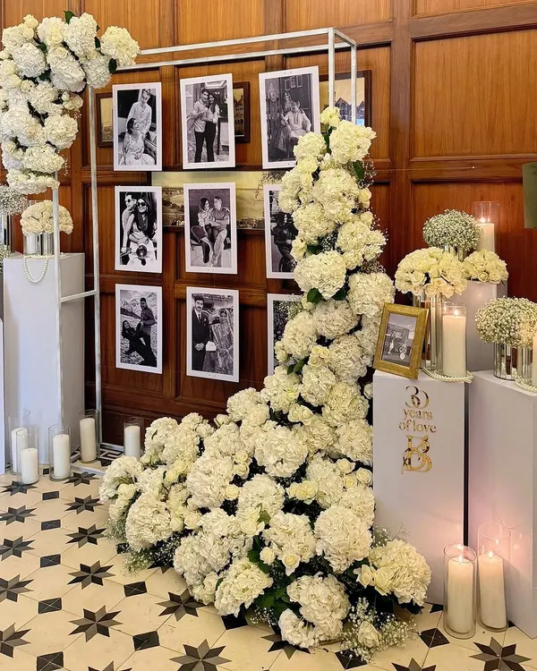 For a 30th anniversary, we created this elegant memory wall. A cascade of white hydrangeas frames a collection of the couple's photos, creating a beautiful and sentimental focal point grounded by the warm glow of candles.