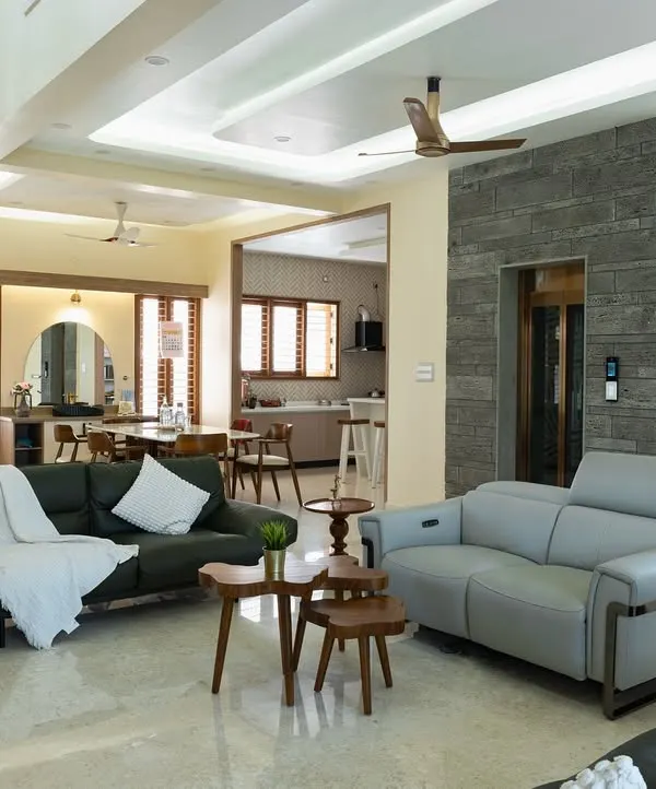 An expansive open-plan villa interior where the living and dining areas flow seamlessly. The high ceiling, marble flooring, and mix of modern sofas create a feeling of spacious, airy luxury.