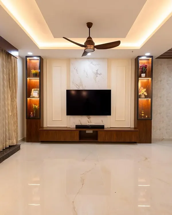 This living room features a sophisticated TV wall with a marble-finish panel and dark wood accents. The vertical display cabinets are backlit to highlight decor, creating a luxurious and balanced focal point.