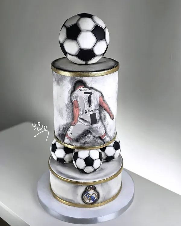 A magnificent three-tiered football cake for a true Cristiano Ronaldo fan. This cake features a hand-painted portrait, the Real Madrid logo, and realistic footballs, making it a champion's choice.
